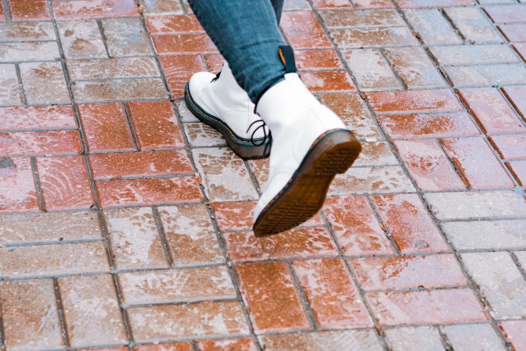 A,Person,Wears,Big,White,Boots,At,The,Wet,Sidewalk